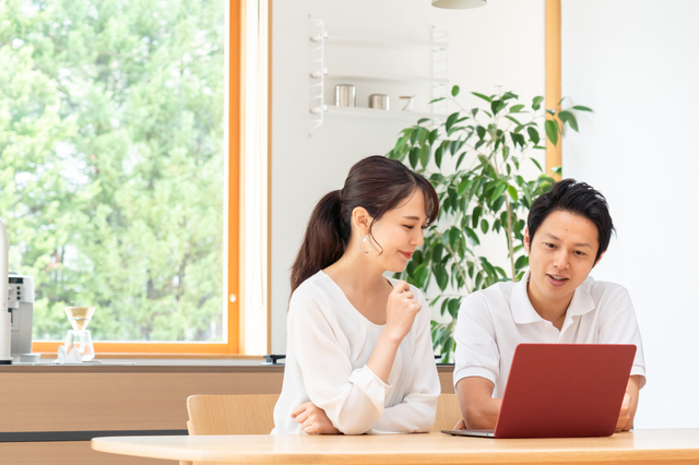 リビングでパソコンを見る夫婦